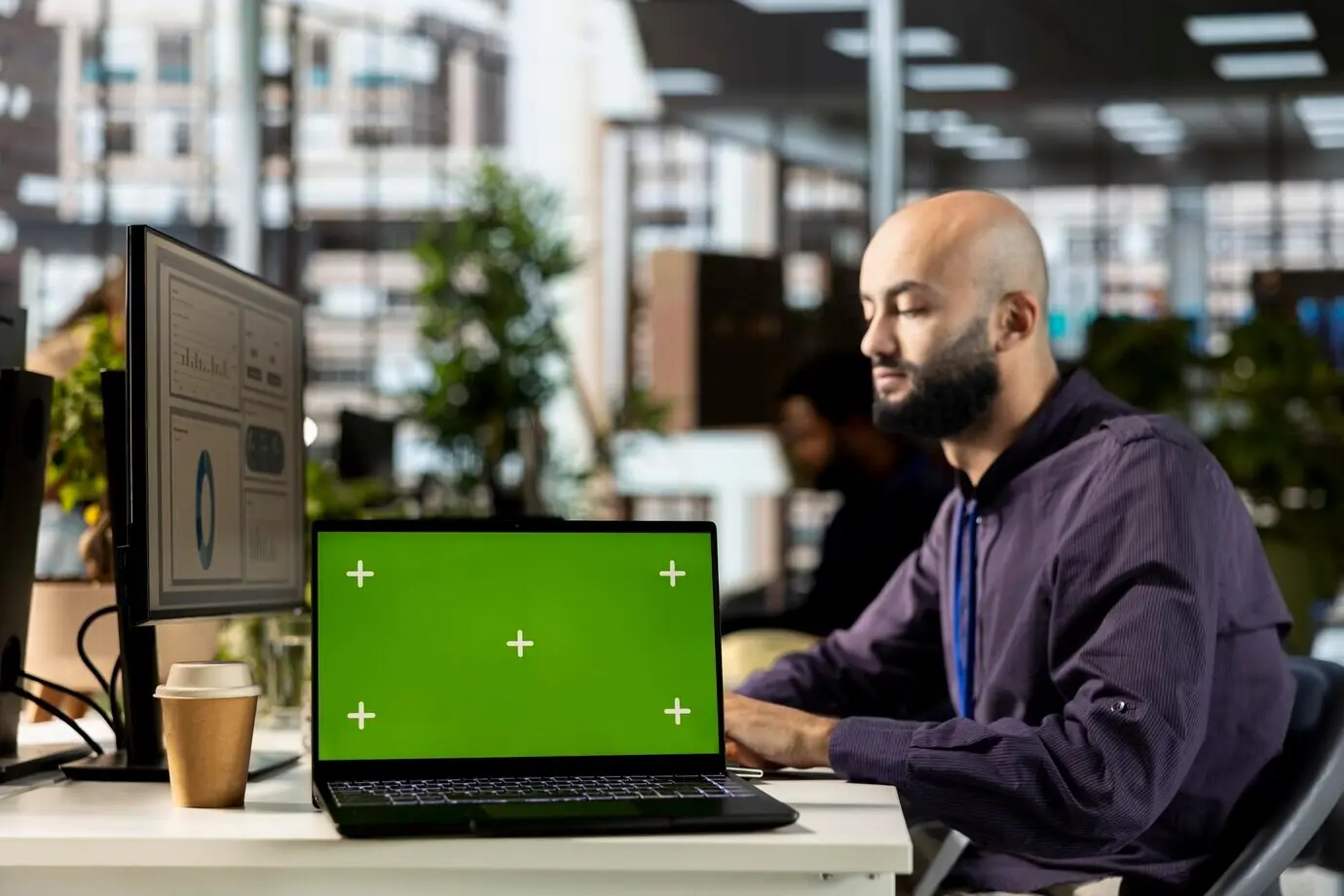 Молодой корпоративный аналитик занимается финансовыми задачами рядом с хромакейным экраном.